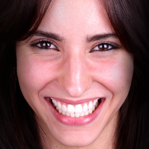 A young woman with long hair smiling happily to show her new smile after dental treatment with Digital Smile Design