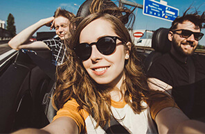 A group of young people smiling as they test drive a new car