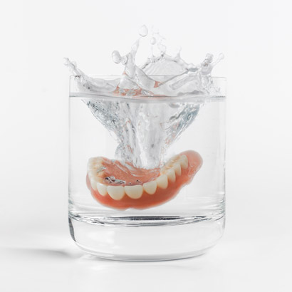 A set of dentures in a glass of water